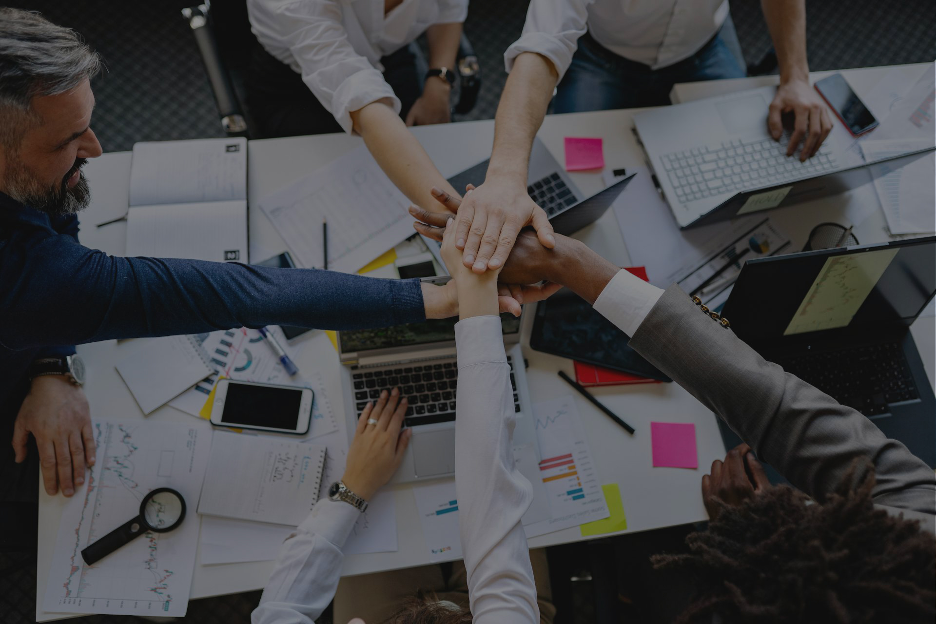 Team members putting their hands together in the centre of a table